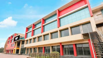 Un edificio de varios pisos con un diseño arquitectónico moderno, que destaca por una llamativa combinación de rojo y beige.