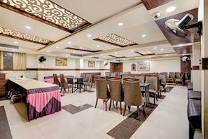 A restaurant with multiple tables and chairs, ceiling fans, and decorative lighting fixtures.