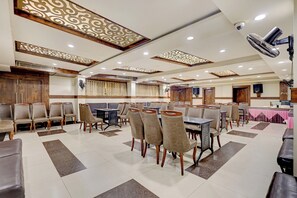 A spacious dining area with multiple tables and chairs, decorative ceiling panels, and recessed lighting.