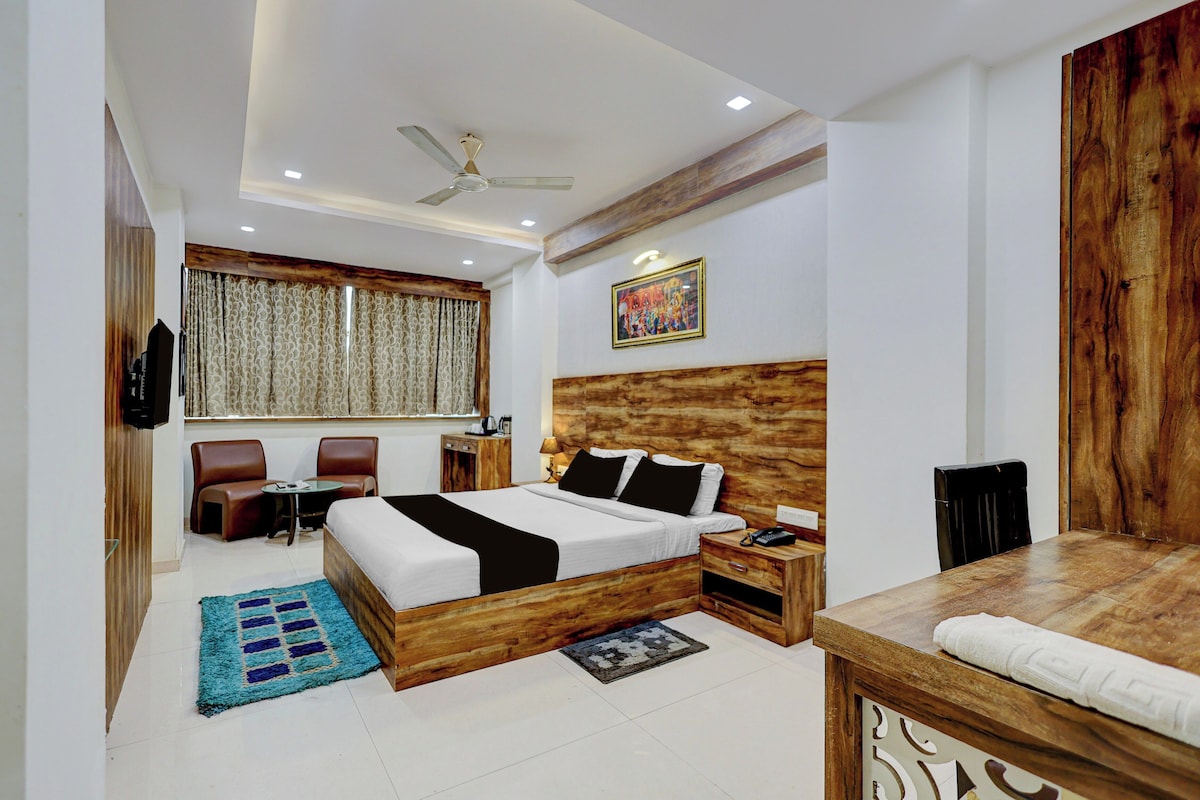 A hotel room with a bed, a desk, a chair, a TV, and a ceiling fan.