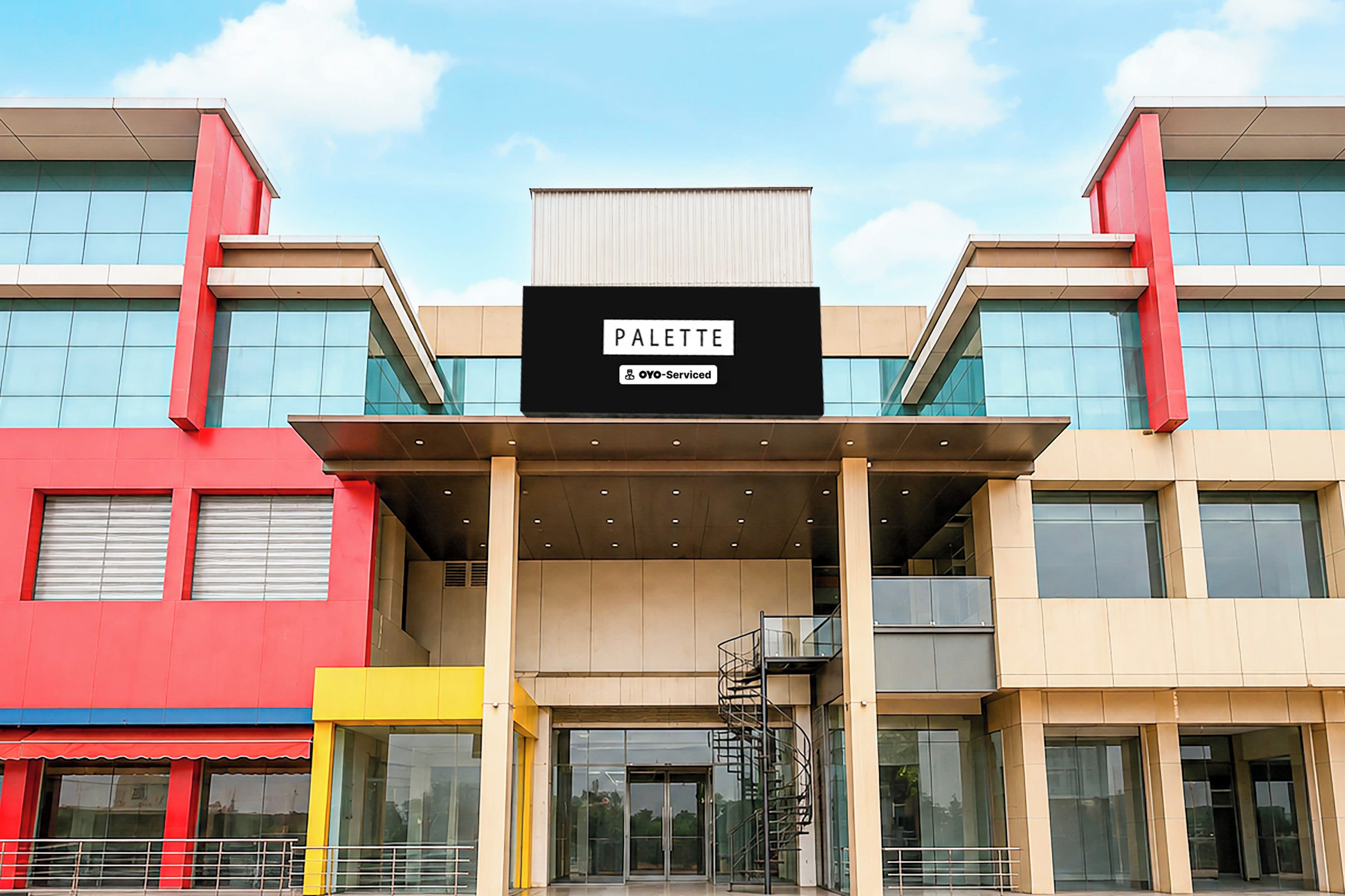 A modern building with a sign reading 'PALETTE' and 'OYO-Serviced' indicating a hotel or serviced apartment.