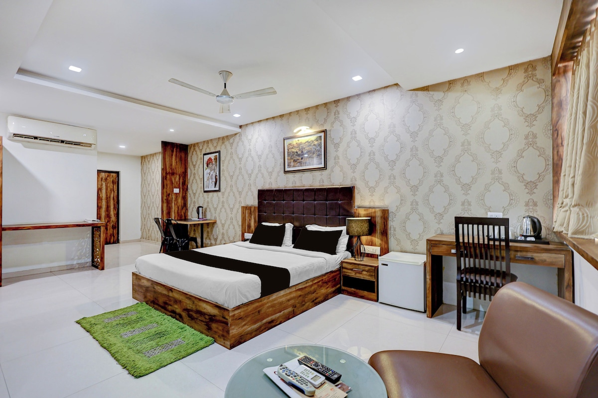 A modern bedroom with a large bed, a desk, a chair, and a ceiling fan.