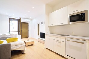 A modern kitchen with a built-in microwave, a dining area with a sofa and a coffee table, and a TV in the living room. - AT Arriba 5 - University A Center (Salamanca)
