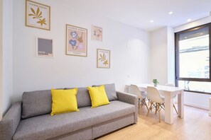 A modern living room with a grey sofa, yellow cushions, and a dining area with a white table and chairs. - AT Arriba 5 - University A Center (Salamanca)