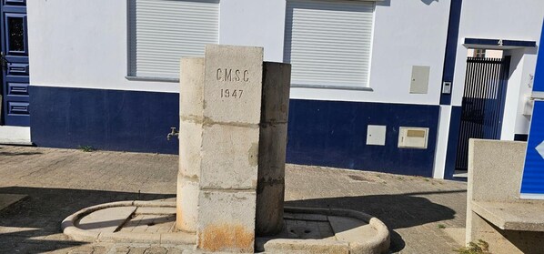 A stone monument with 'CMSC 1947' engraved on it, located in front of a building with a blue and white facade.