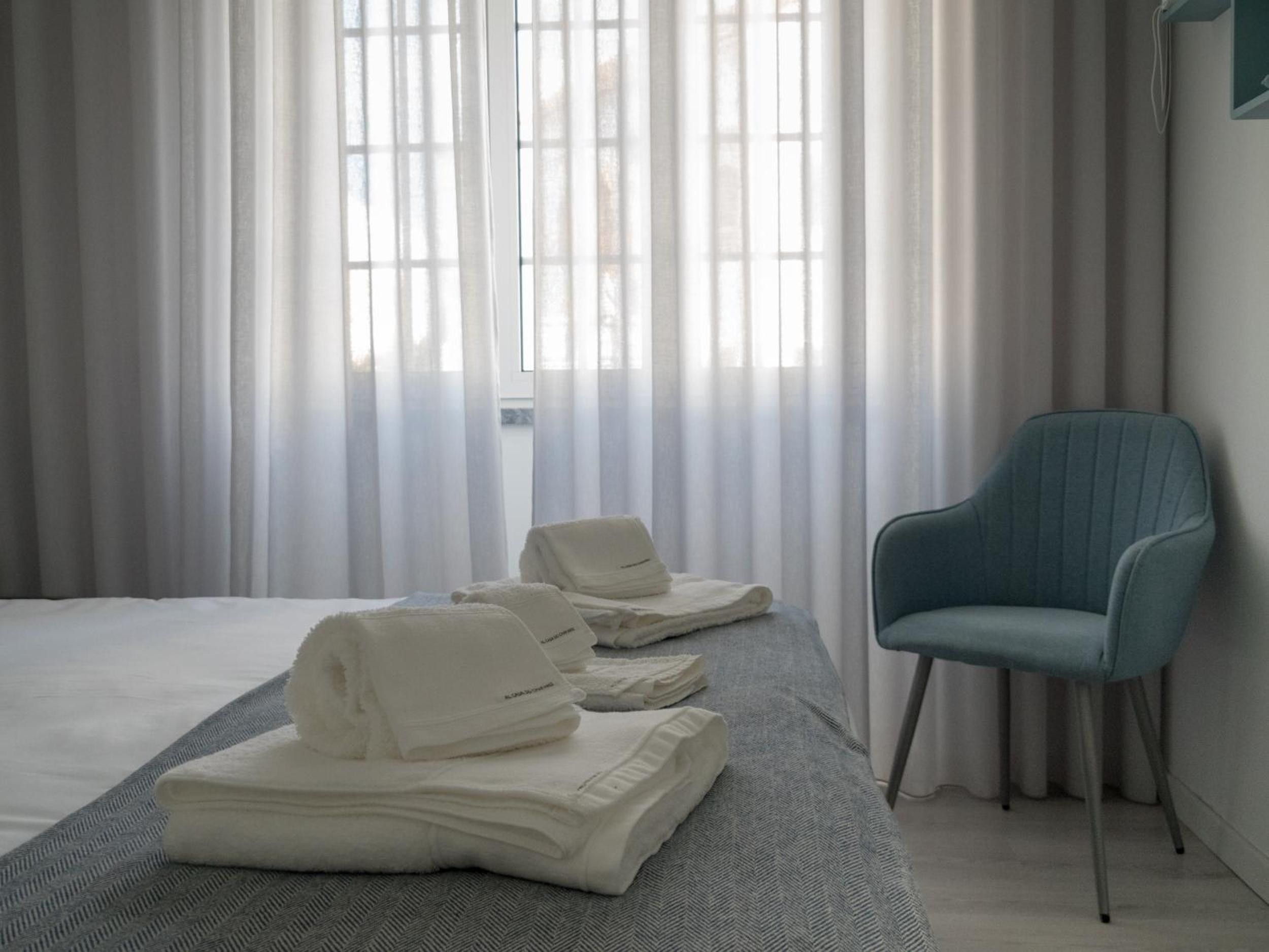 A hotel room with a bed, a chair, and towels.