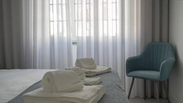 A hotel room with a bed, a chair, and towels.