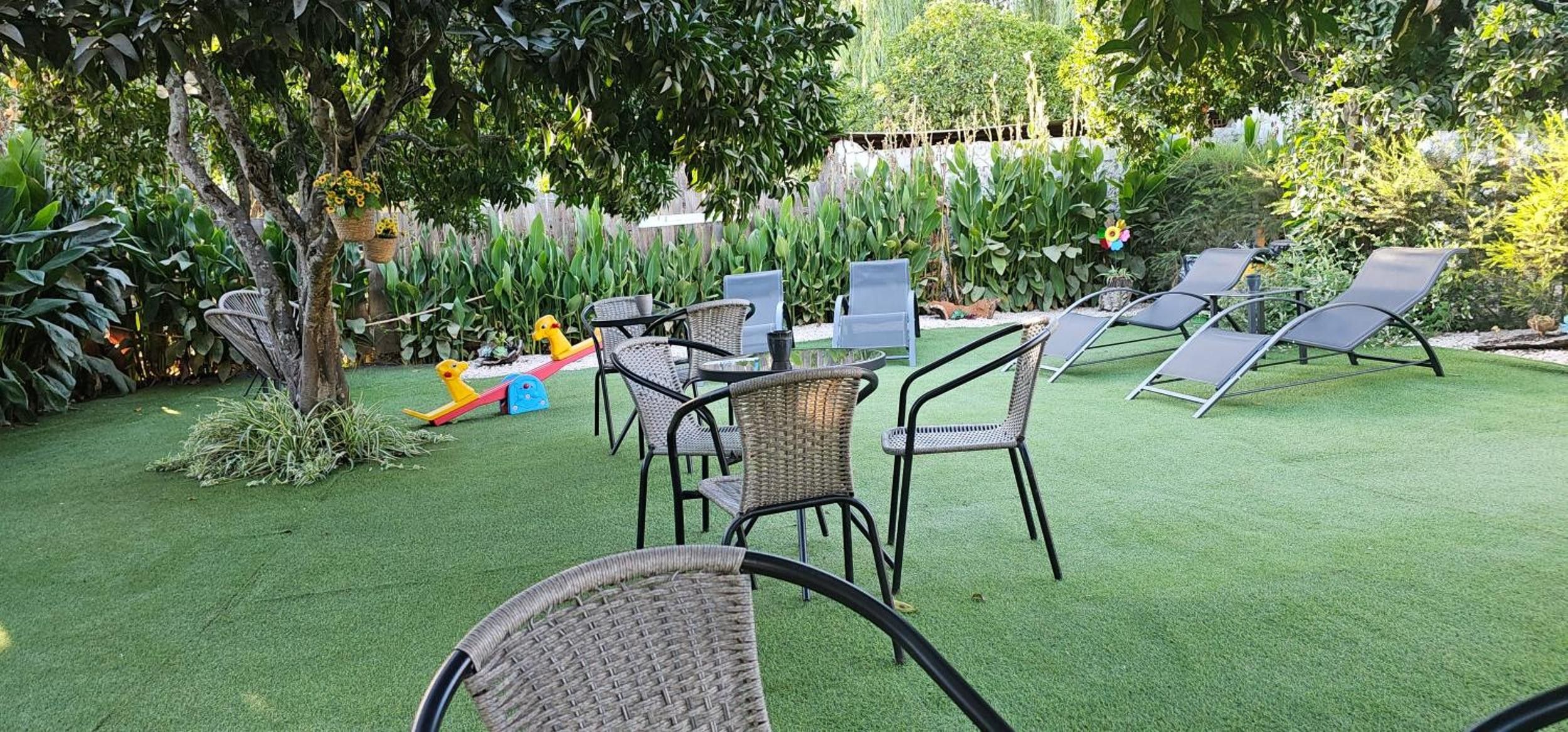 An outdoor patio area with artificial grass, wicker furniture, and a play area with toys.