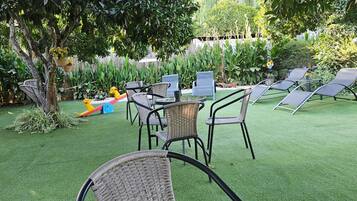An outdoor patio area with artificial grass, wicker furniture, and a play area with toys.