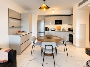 Een moderne keuken met een centraal eiland, witte kasten en een eethoek met een ronde tafel en stoelen.