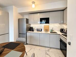 A modern kitchen with a built-in microwave, stainless steel refrigerator, and a wooden cutting board. - Solemare 402 by Avecoeur (Villeneuve-Loubet)