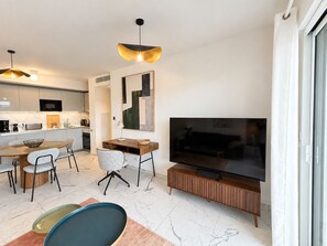 Een moderne woonruimte met een eethoek, keuken en een televisie op een houten standaard.