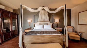 A four-poster canopy bed with two bedside tables, a chair, and a large mirror.