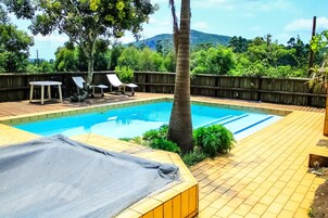 Una piscina rectangular con cubierta de madera, rodeada por una valla de madera, y vista a un paisaje montañoso.