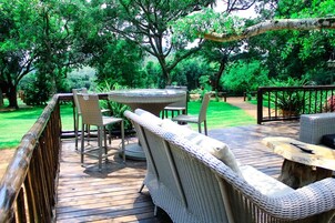 Una terraza exterior con mobiliario de mimbre, incluyendo sillas y una mesa.