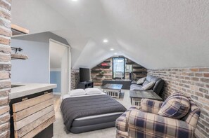 A compact room with a loft bed, a sofa, a small table, and a TV. - The Four Doors Upstairs-WIFI-TV-Kitchenette (Oak Grove)