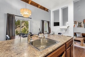 A modern kitchen with a granite countertop, stainless steel sink, and a pendant light. - Apres Tahoe 4BR Mountain Home (Stateline)