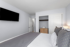 A bedroom with a bed, a television mounted on the wall, a wardrobe, and a door leading to another room. - Apres Tahoe 4BR Mountain Home (Stateline)