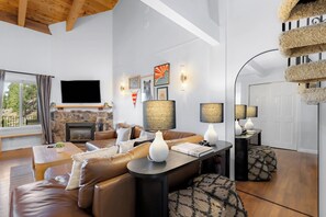 A modern living room with a fireplace, leather sofa, and a flat-screen TV. - Apres Tahoe 4BR Mountain Home (Stateline)