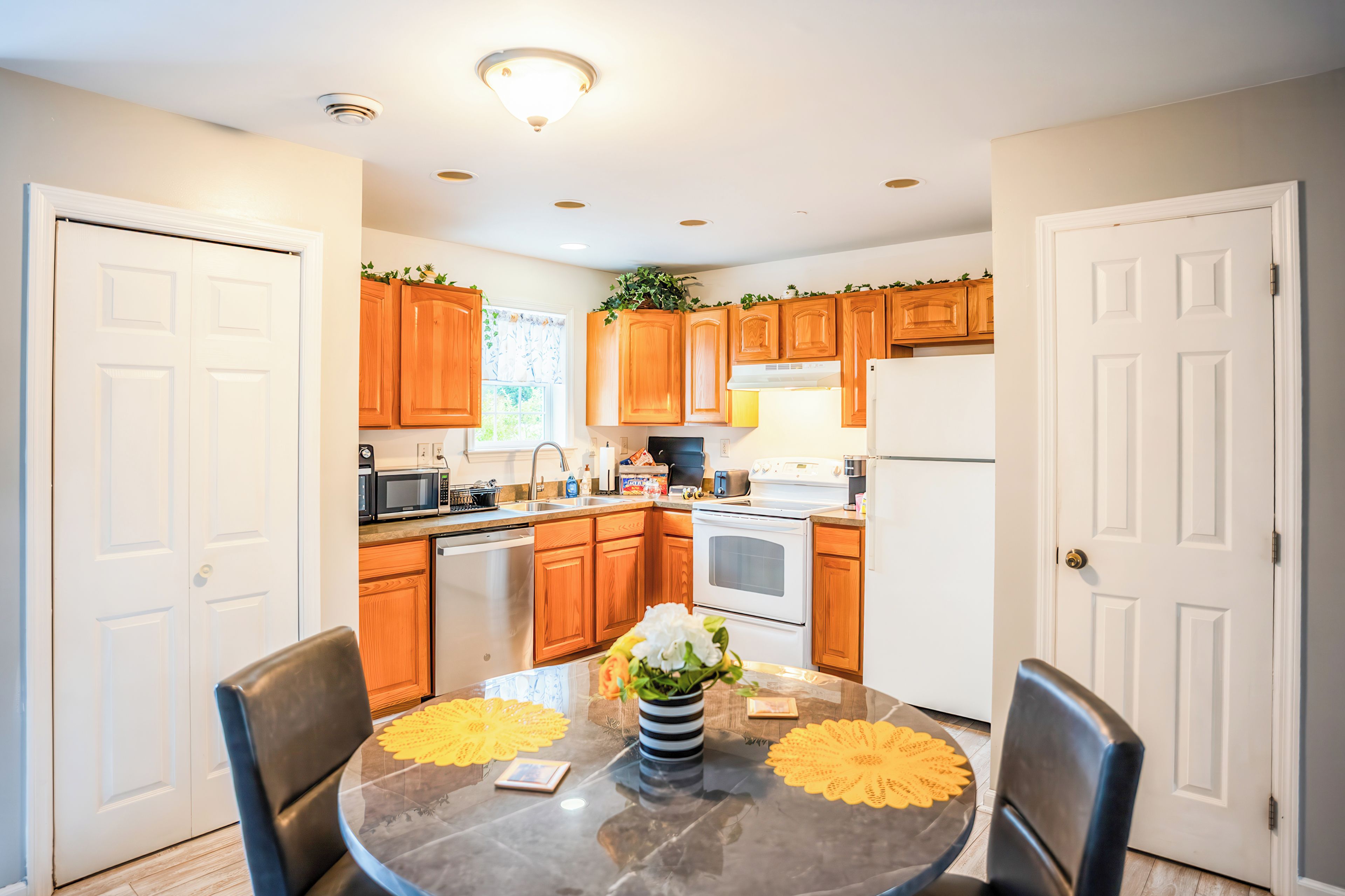 A modern kitchen with wooden cabinets, stainless steel appliances, and a dining table with yellow placemats.