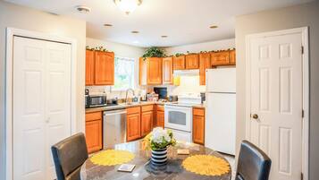 A modern kitchen with wooden cabinets, stainless steel appliances, and a dining table with yellow placemats.