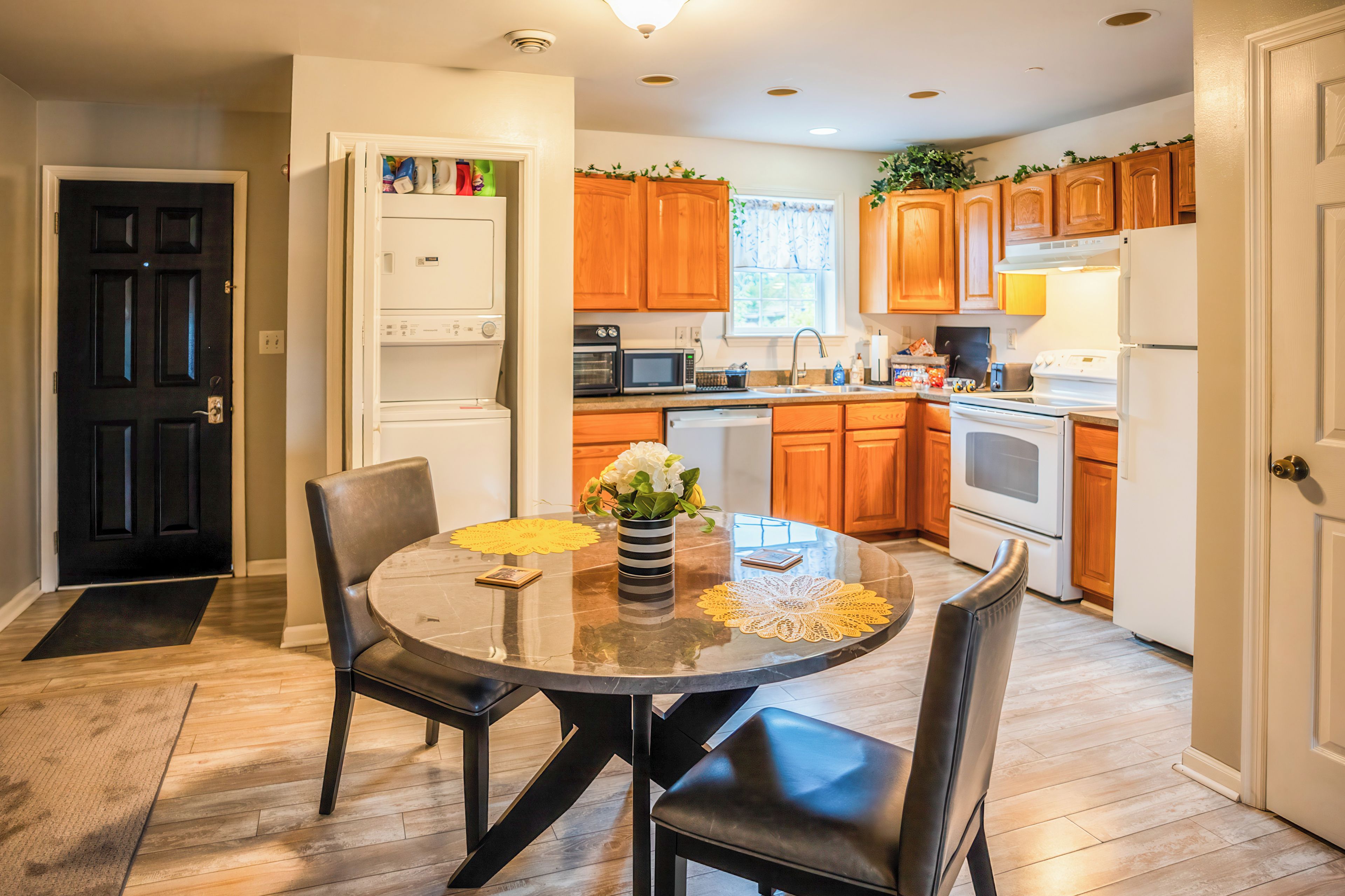 A modern kitchen with wooden cabinets, a dining table with chairs, and a refrigerator.