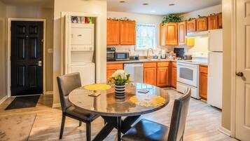 A modern kitchen with wooden cabinets, a dining table with chairs, and a refrigerator.