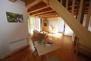 A wooden interior with a dining table, chairs, a television, and a staircase. - Charming house in Quercy – private heated pool (15×6 m) and separate guesthouse (Roquecor)