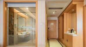 A hotel bathroom with a glass-enclosed shower, a sink, and wooden cabinets. - Vienna Hotel (Chengdu)
