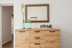 A wooden dresser with drawers and a mirror above it. There are two glass jars with plants on the dresser. - AT Macías Home, Cáceres Center (Cáceres‎)