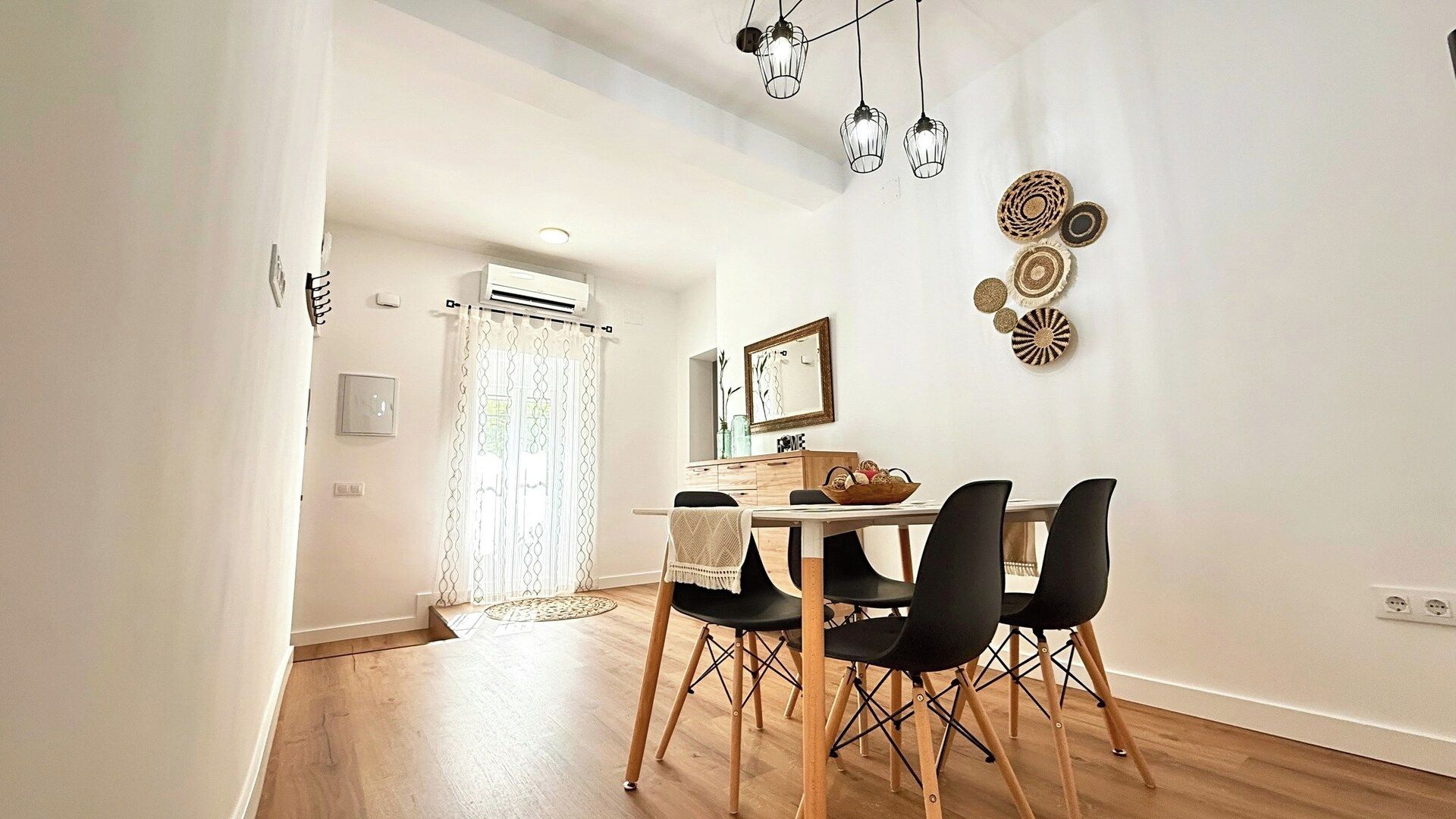 A dining area with a wooden table, black chairs, and a ceiling light fixture.