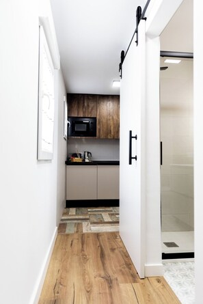 A narrow hallway leading to a kitchen with wooden cabinets, a microwave, and a coffee machine. - AT Macías Home, Cáceres Center (Cáceres‎)