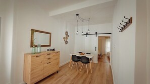 A modern dining area with a wooden cabinet, a white table, and black chairs. - AT Macías Home, Cáceres Center (Cáceres‎)