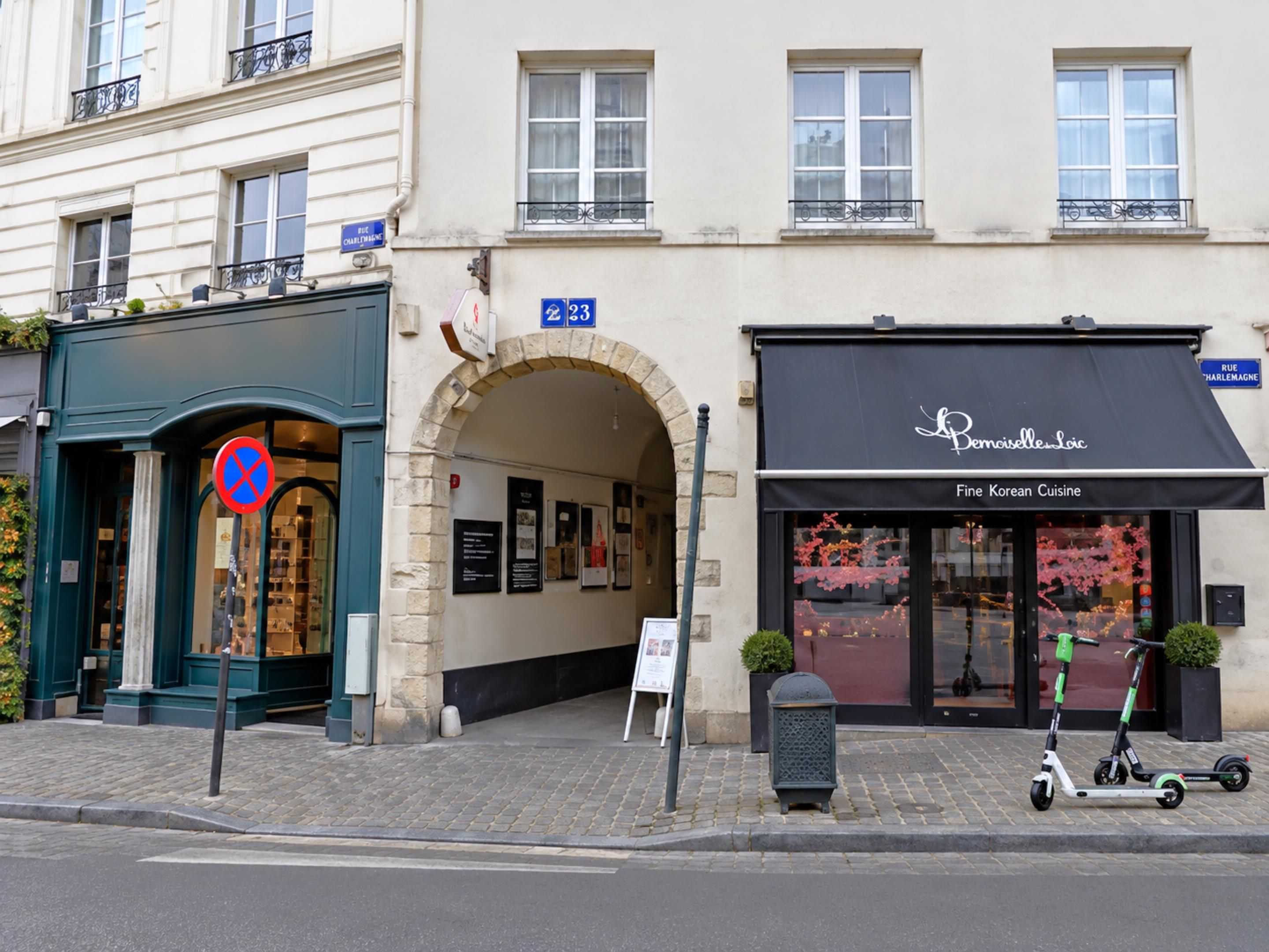 Straatbeeld met een gebouw, voorzien van een zwart luifel en borden met 'Fine Korean Cuisine', 'Rue Charlemagne' en een verbodsbord voor parkeren.