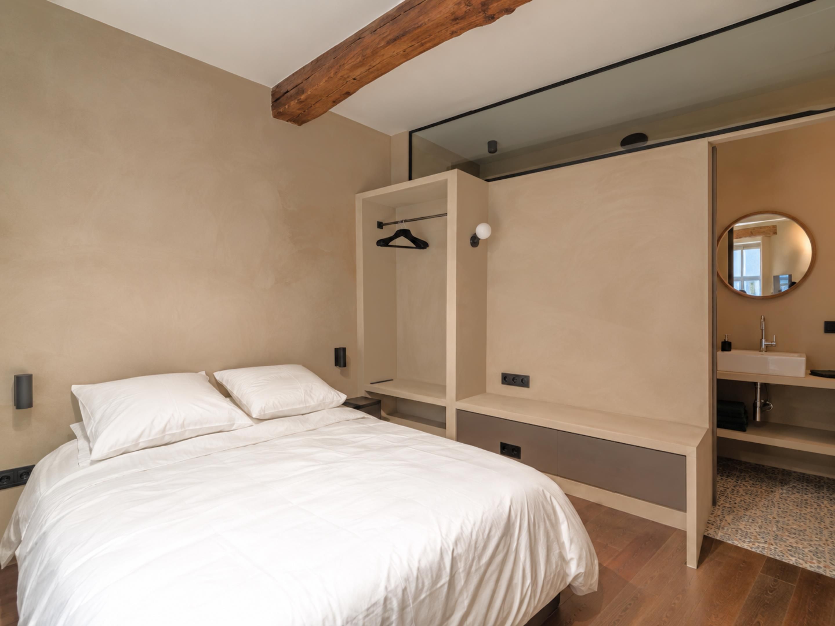 A bedroom with a bed, a wardrobe with a mirror, and a built-in shelf.