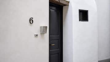 A white exterior wall with a black door, a small window, and a number '6' sign.