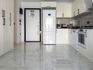 A modern kitchen with white cabinetry, a stainless steel refrigerator, an oven, and a microwave. - Qoople Elize C15 - Cozy 1-bedroom apartment in Alanya (Alanya)