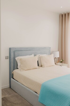 A bedroom with a bed, pillows, a bedside table with a lamp, and a window with curtains. - Casa da Venda by Lethes Legacy (Refóios do Lima)
