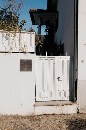Um prédio branco com um portão de metal e uma pequena placa com a palavra 'Pao'.