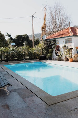A swimming pool with a tiled deck, surrounded by potted plants and a building with a tiled roof. - Casa da Venda by Lethes Legacy (Refóios do Lima)