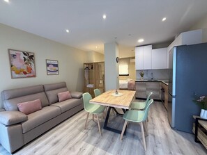 A modern living room with a sofa, a dining table, and chairs. There is a kitchen area with cabinets and a refrigerator. - Aires de Salamanca Calixto (Salamanca)