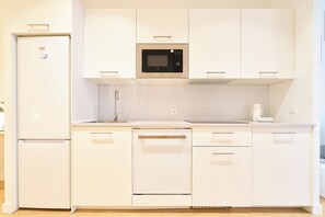Cozinha moderna com armários brancos, micro-ondas embutido, geladeira e lava-louças.