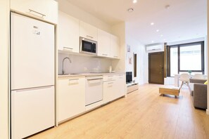 A modern kitchen with a microwave, sink, and cabinets. There is a dining area with a table and chairs. - AT Arriba 5 - University B Center (Salamanca)