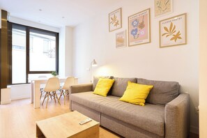 A modern living room with a grey sofa, yellow cushions, a wooden coffee table, and a dining area with a white table and chairs. - AT Arriba 5 - University B Center (Salamanca)