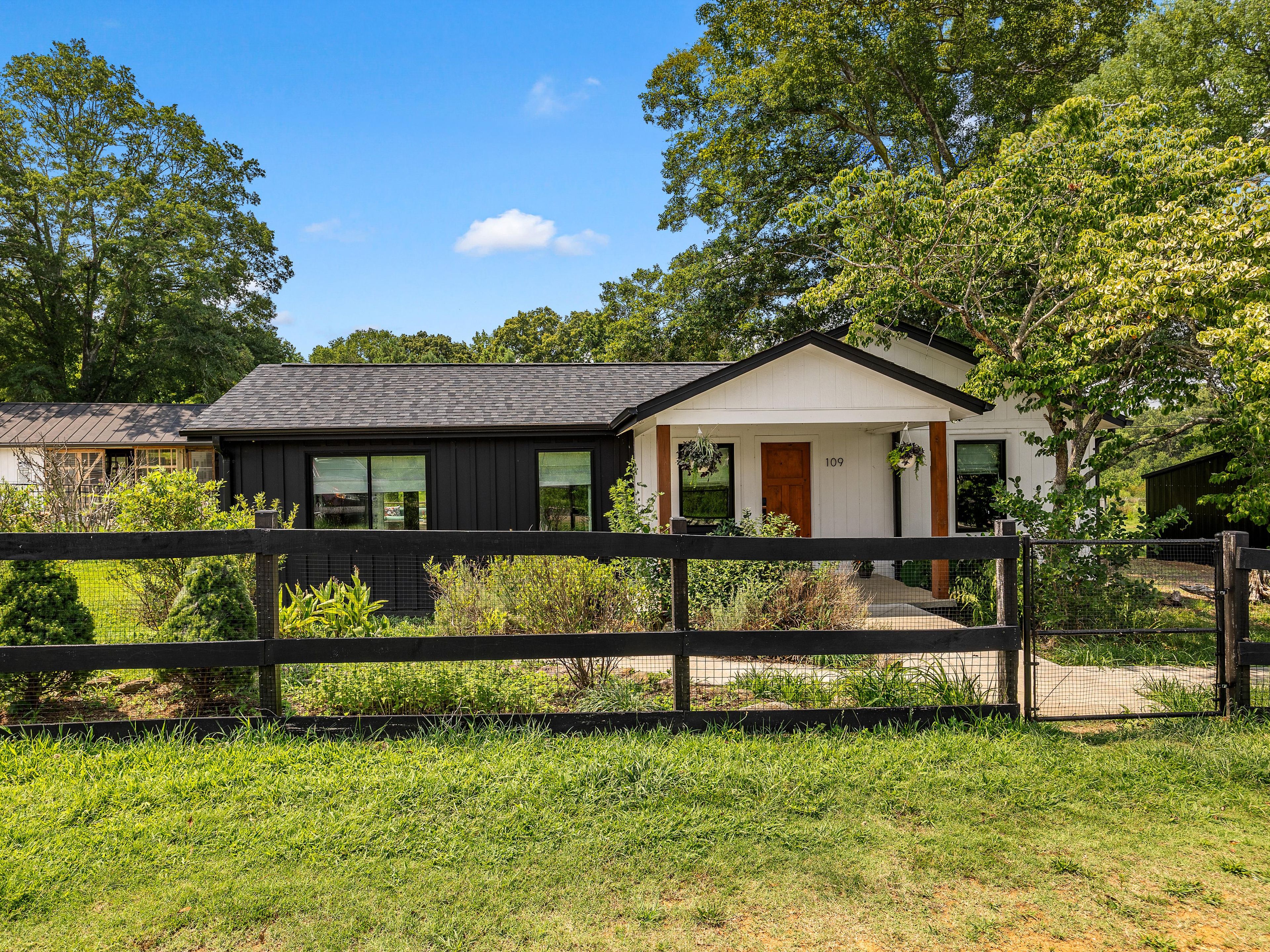 A modern two-story house with a black exterior, a white front porch, and a number '109' on the door.