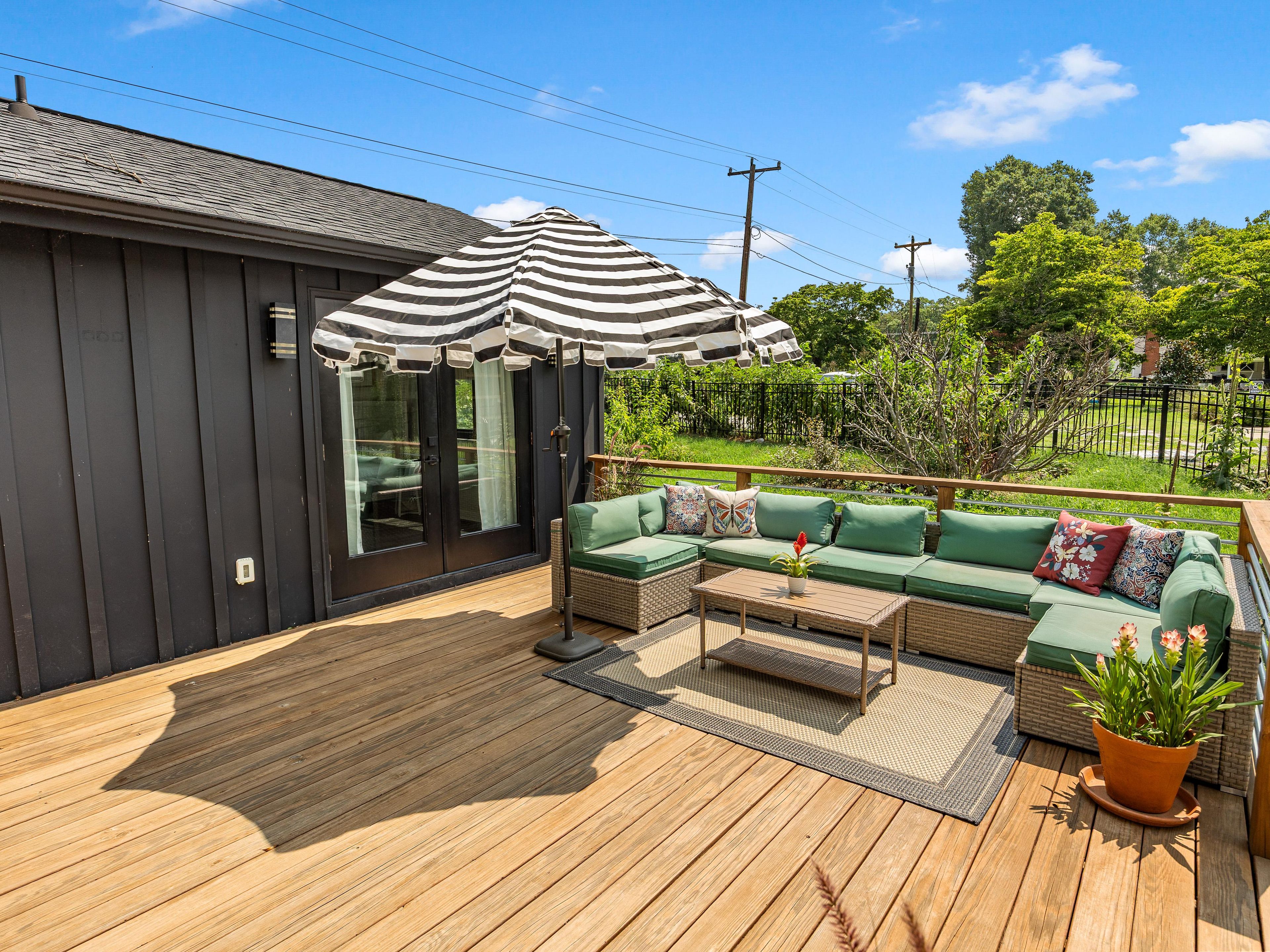 A deck with a sofa, a table, and a striped umbrella.
