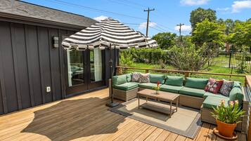 A deck with a sofa, a table, and a striped umbrella.