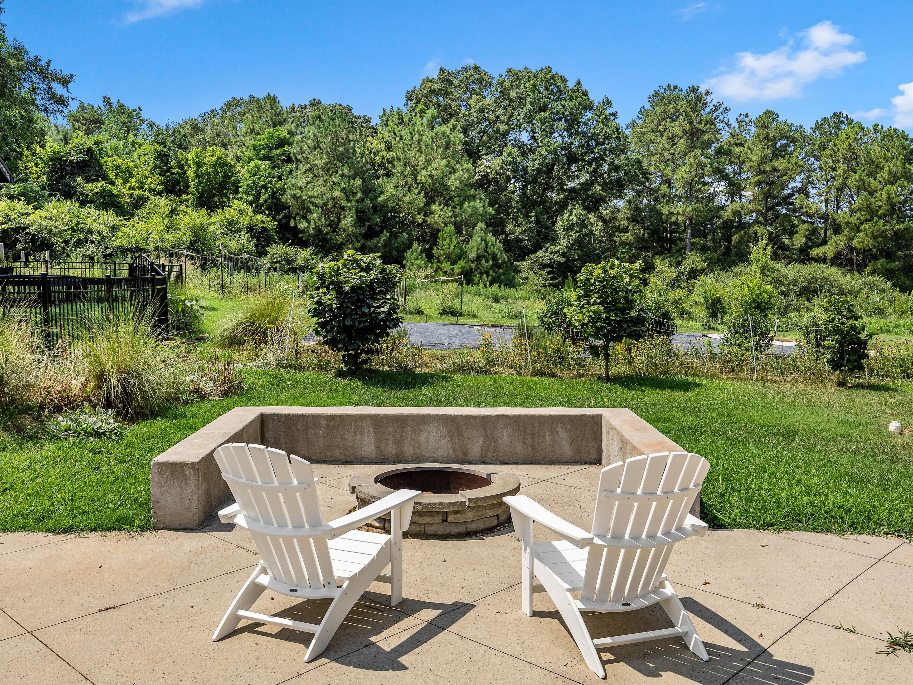 An outdoor seating area with two Adirondack chairs and a fire pit.