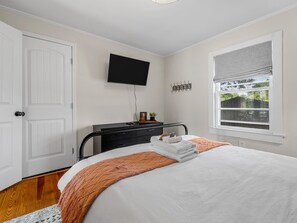 Un dormitorio con cama, cómoda, televisor y ventana con vista.