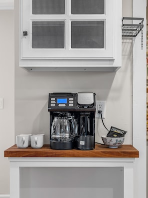 Een koffiezetapparaat op een houten aanrecht met een witte kast erboven.